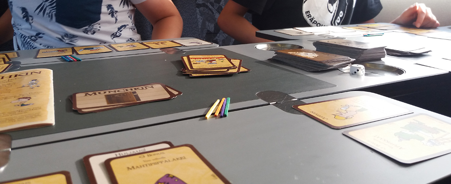 Munchkin-peli tanskalaisen EC-junan pöydällä, levelit merkittynä puutikuilla.